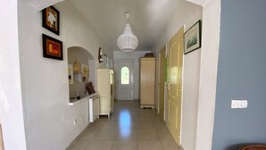 A hallway with a tiled floor, a white door at the end, and a green chair to the right. - Villa with breathtaking view of the Massif des Maures (Vidauban)
