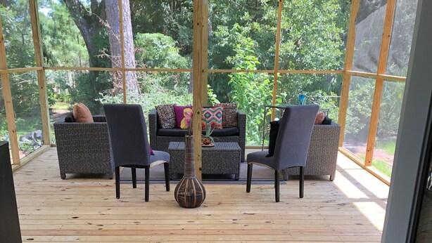 A covered outdoor seating area with wicker furniture and a decorative vase. - Home Away from Home (Wilmington Island)
