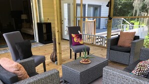 A covered outdoor seating area with wicker furniture and a potted plant. - Home Away from Home (Wilmington Island)