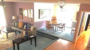 A living room with a sofa, coffee table, and a dining area with chairs and a table. - Home Away from Home (Wilmington Island)