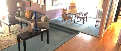 A living room with a sofa, coffee table, and a dining area with chairs and a table.