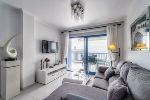 Ein modernes Wohnzimmer mit Sofa, Fernseher und einem Balkon mit Blick.