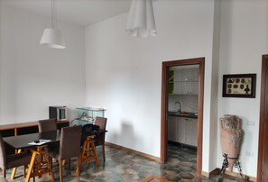 Une cuisine moderne avec un sol carrelé, un coin repas comprenant une table et des chaises, et un grand vase décoratif.