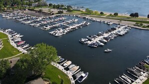 A marina with multiple docks and boats, surrounded by greenery and a clear view of the lake.