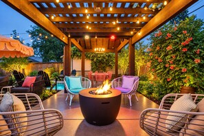 An outdoor patio with a fire pit, seating, and a pool.