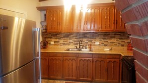 A kitchen with wooden cabinets, a stainless steel refrigerator, and a tiled backsplash. - Central, Modern, Fast Wi-fi. Beach, food, nightlife & market access w/in 3 km (Ensenada)