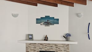 A fireplace with a stone facade, a mantel with a framed picture and a small statue, and a wall-mounted artwork above. - Central, Modern, Fast Wi-fi. Beach, food, nightlife & market access w/in 3 km (Ensenada)