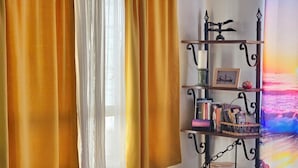 A cozy living room with a striped sofa, a decorative basket, and a bookshelf with books and a framed picture. - Central, Modern, Fast Wi-fi. Beach, food, nightlife & market access w/in 3 km (Ensenada)
