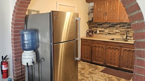A kitchen with a stainless steel refrigerator, a water dispenser, wooden cabinets, and a tiled floor. - Central, Modern, Fast Wi-fi. Beach, food, nightlife & market access w/in 3 km (Ensenada)