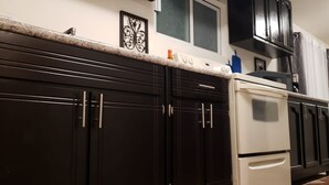 A kitchen with dark cabinets, a white refrigerator, and a microwave. - Pura Vida Casita Retreat: Temp-control heat+more modern conveniences for comfort (Ensenada)