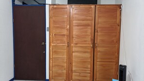 A room with a brown door, a blue-framed window, and a black air conditioning unit. - Entire Comfy apartment for your,  5 min SJO airport (Alajuela)