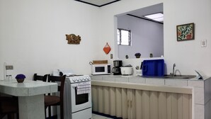A compact kitchen with white appliances, a dining table, and chairs. - Entire Comfy apartment for your,  5 min SJO airport (Alajuela)