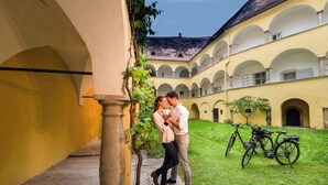 Un patio con un edificio amarillo, una bicicleta y una pareja besándose.
