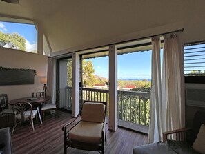 Enjoy the serene view from this room's spacious balcony with a seating area and large window.