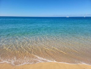 Une plage avec une eau claire et peu profonde et un rivage sablonneux.