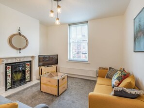 Una sala de estar con chimenea, televisor, sofá y ventana con persianas.