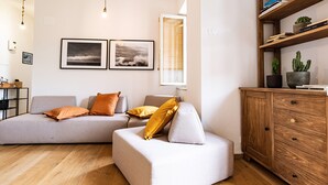Una sala moderna con un sofá modular, un aparador de madera y dos cuadros enmarcados en la pared.