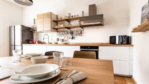 Una cocina moderna con armarios de madera, electrodomésticos de acero inoxidable y una mesa de comedor de madera dispuesta con platos, vasos y cubiertos.