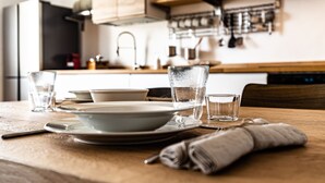 Una cocina con una mesa de madera preparada para comer, incluyendo platos, tazones y vasos.
