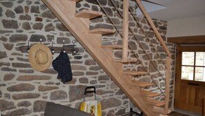 A wooden staircase with a stone wall background, a hat, and a bag hanging on hooks. - La Maison de Félicie (Saint-Pol-de-Léon)