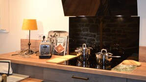 A kitchen counter with a toaster, a coffee maker, a kettle, and a cutting board. - La Maison de Félicie (Saint-Pol-de-Léon)