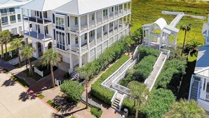 Un hôtel à plusieurs étages, doté d’une façade blanche, situé près d’une plage avec une promenade en bord de mer et des palmiers.