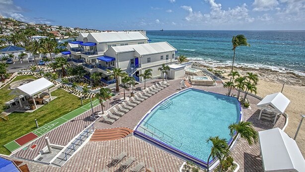 Un resort con una piscina grande, acceso a la playa y vista al océano.