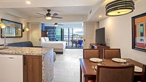 Habitación de hotel moderna con cocina, mesa de comedor y balcón con vistas.
