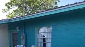 A teal building with a small patio area featuring white metal chairs and a table. - Peaceful, close to water attractions & Fishing (Panama City)