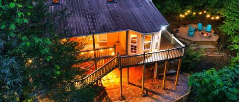 A house with a deck, a fire pit, and string lights.