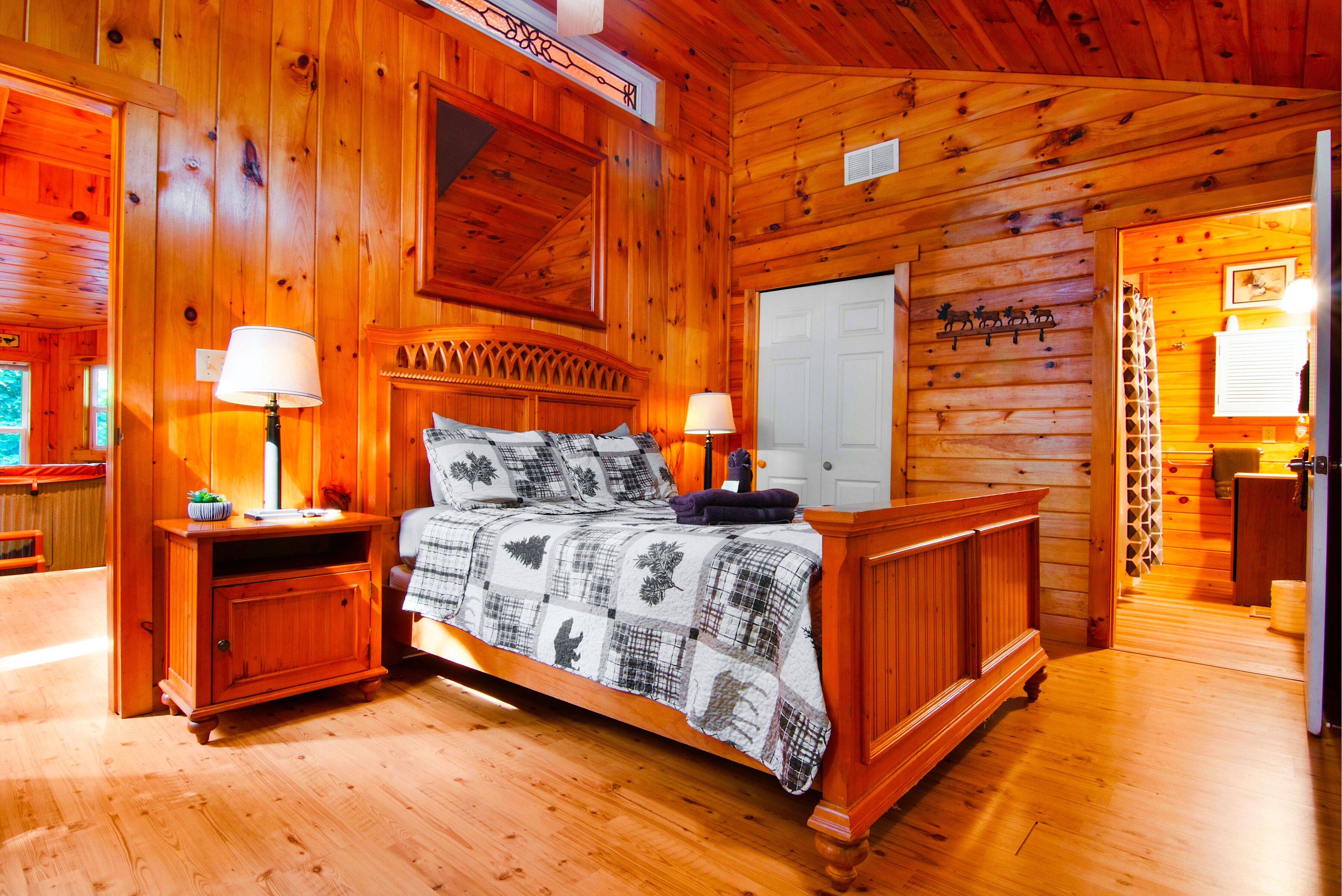 A wooden cabin bedroom with a bed, two bedside tables, a nightstand, and a dresser.