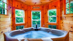 A wooden cabin with a hot tub, large windows, and a sign indicating a deer crossing. - Cozy Cabin Retreat - Hot Tub, Fireplace & Fire Pit - Minutes from Blue Ridge (Blue Ridge)