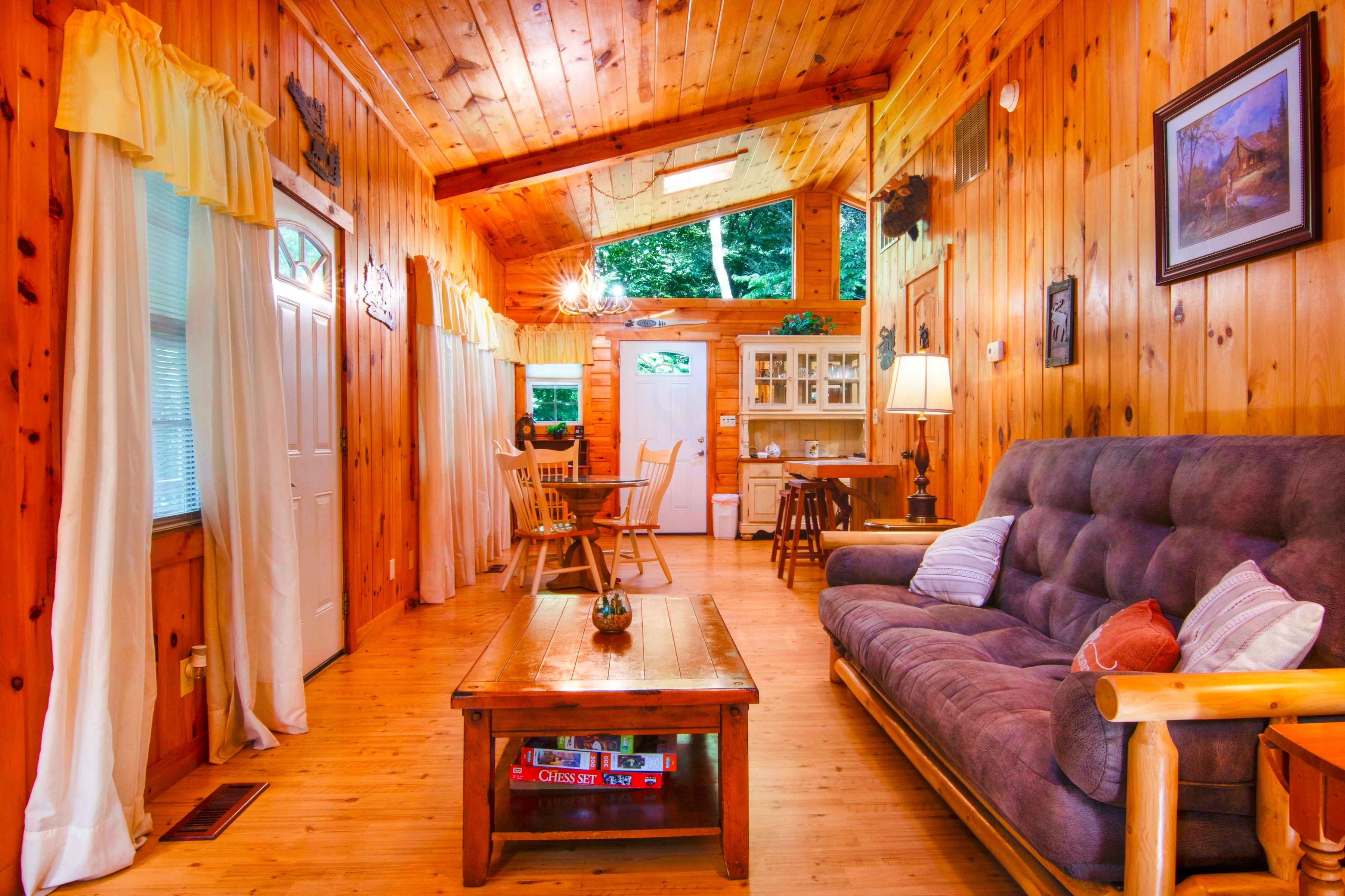 Un intérieur de chalet chaleureux avec un coin repas en bois, un canapé et une cuisine ouverte.