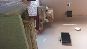 Ett rum med en soffa, ett litet bord, en väggmonterad högtalare och ett eluttag.