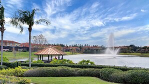 A gazebo with a tiled pathway leading to a lake, surrounded by well-maintained hedges and palm trees. - Bay Lilly Family Villa Close to Parks sleeps 8 (Kissimmee)