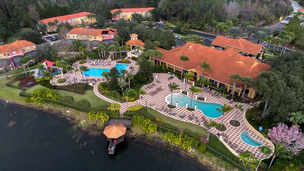 An aerial view of a resort with multiple swimming pools, a dock, and a large umbrella structure. - Bay Lilly Family Villa Close to Parks sleeps 8 (Kissimmee)