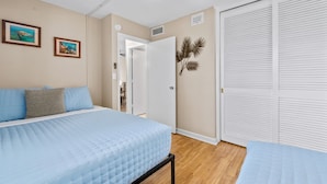 Quarto com cama, ventilador de teto, porta e armário.