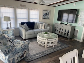 A living room with a sofa, armchair, TV, and decorative items.