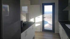 A modern kitchen with white cabinets, a black countertop, and a view of a pool through a door. - VILLA "LA FLORIDA" - WONDERFUL VIEWS - POOL - WIFI (CN)