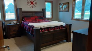 Ein Schlafzimmer mit einem hölzernen Bett, einem Nachttisch, einer Kommode, einem Deckenventilator und einer Wanduhr.