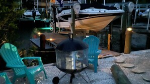 Un espace patio avec des sièges d’extérieur, un barbecue et un quai avec des bateaux.