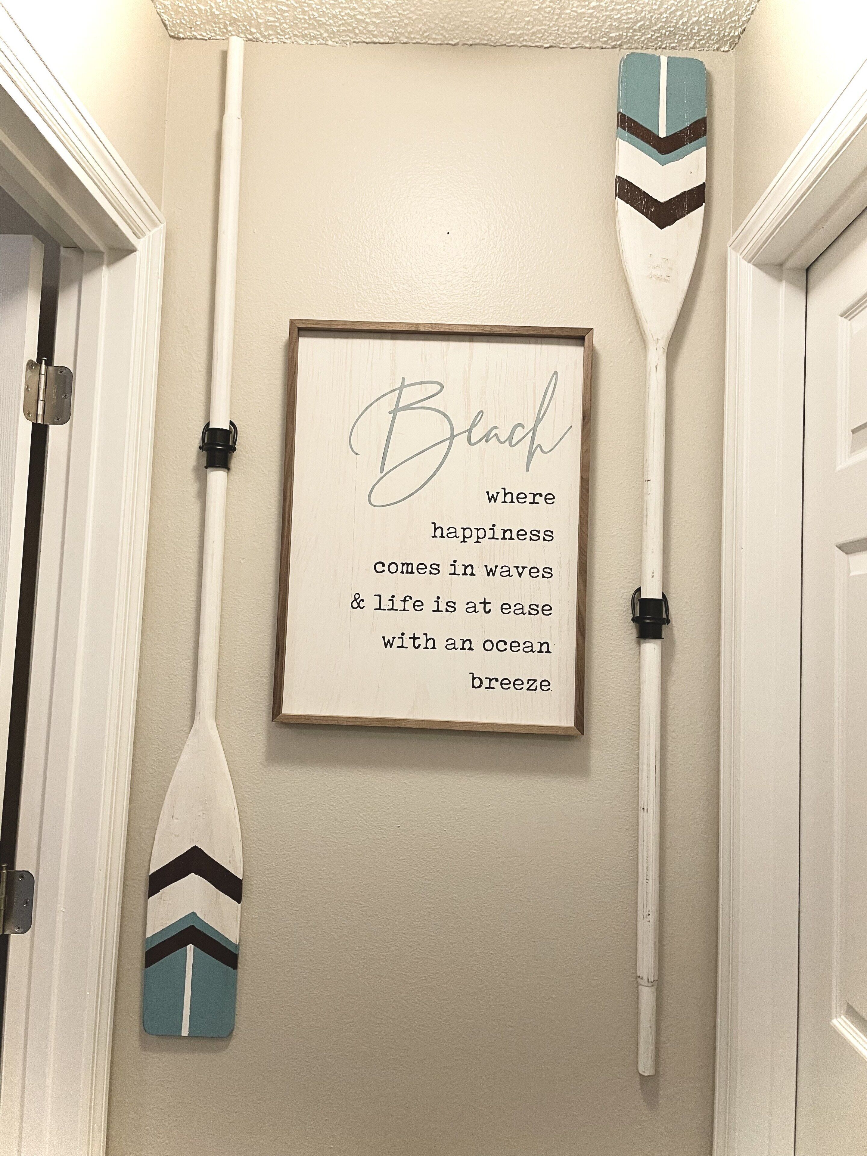 A framed inspirational quote on a wall with two paddleboards leaning against the wall.