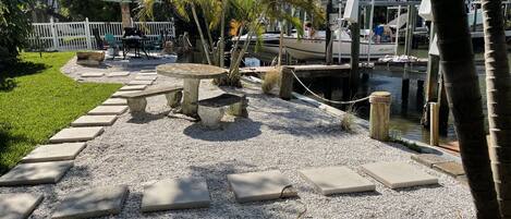 A waterfront patio with stone benches and a dock.