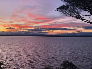A calm body of water reflecting a sunset sky with clouds.