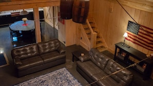 A cozy living room with a brown leather sofa, a patterned rug, and a wooden ceiling. - Unique 3 bedroom barn with a fireplace and pond (Sarver)