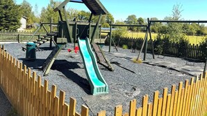 A playground with a slide, swings, and a climbing structure. - Glamping Hut - Sleeps 2, hot tub & parking (Welshpool)