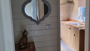 A kitchen with wooden cabinets, a sink, and a decorative mirror. - Glamping Hut - Sleeps 2, hot tub & parking (Welshpool)