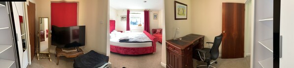 Relax in a spacious room with a large flat-screen TV, comfortable bed, and wooden desk.