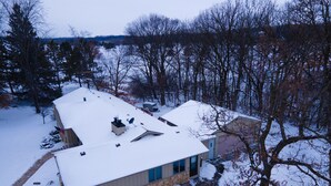 A house with a snow-covered roof, a stone foundation, and a satellite dish.