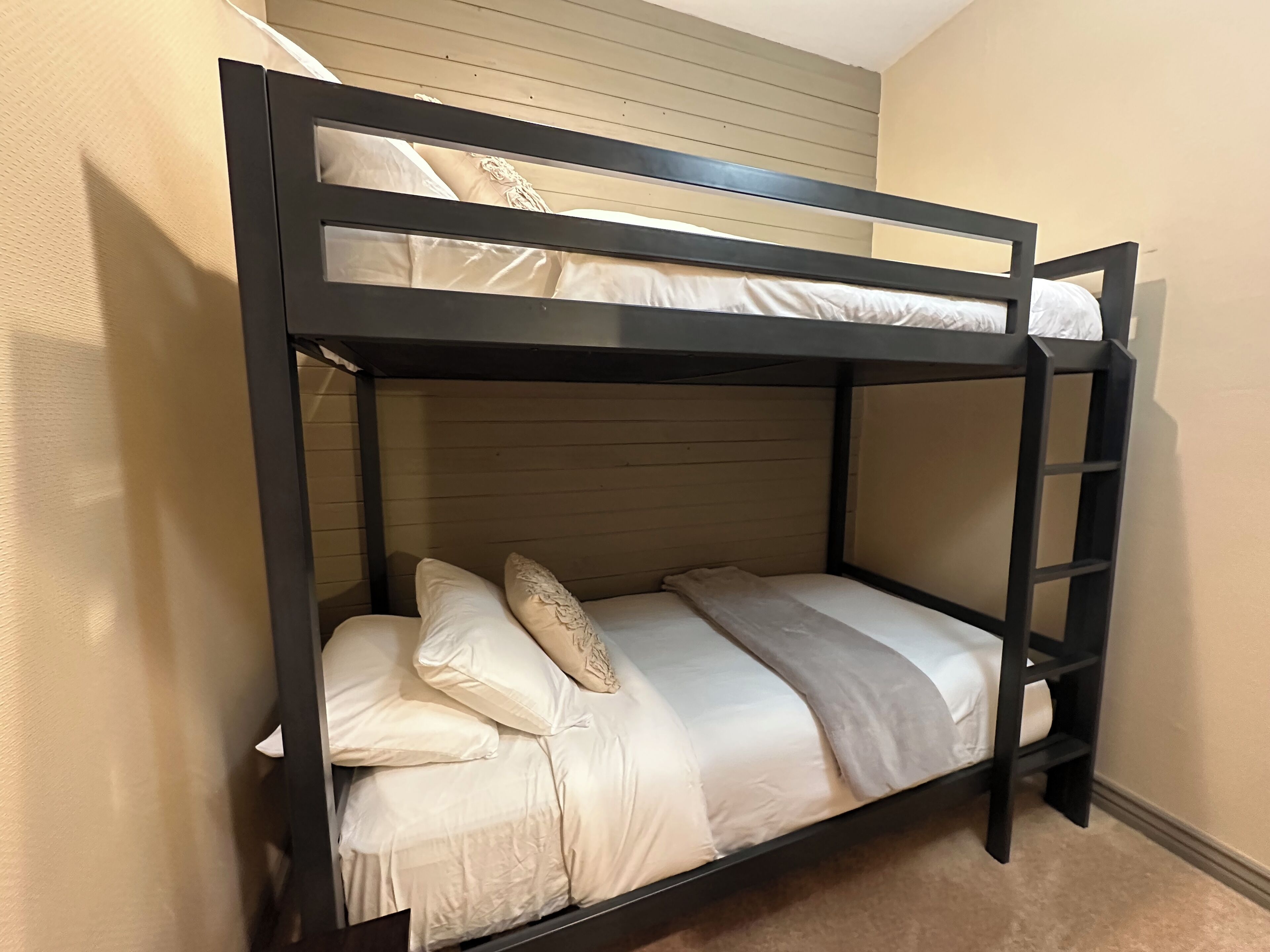Ein Etagenbett mit zwei Schlafstellen, jeweils mit Kissen und Decke.